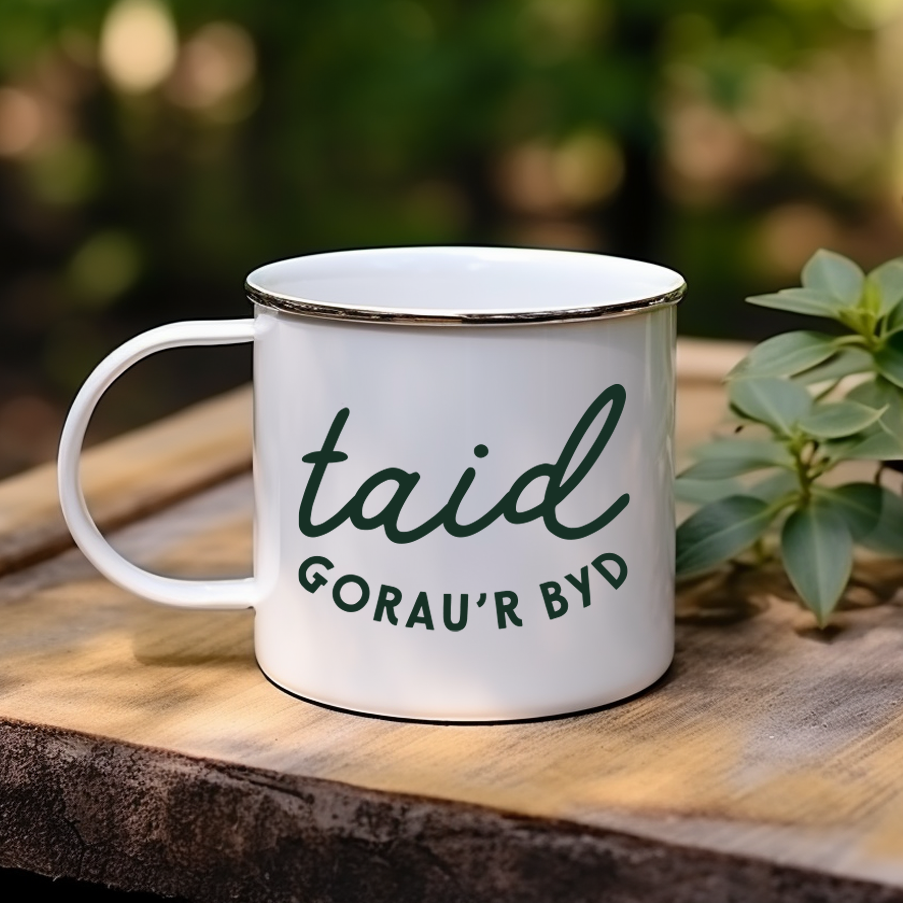 White mug with green text on a wooden surface with a blurred natural background